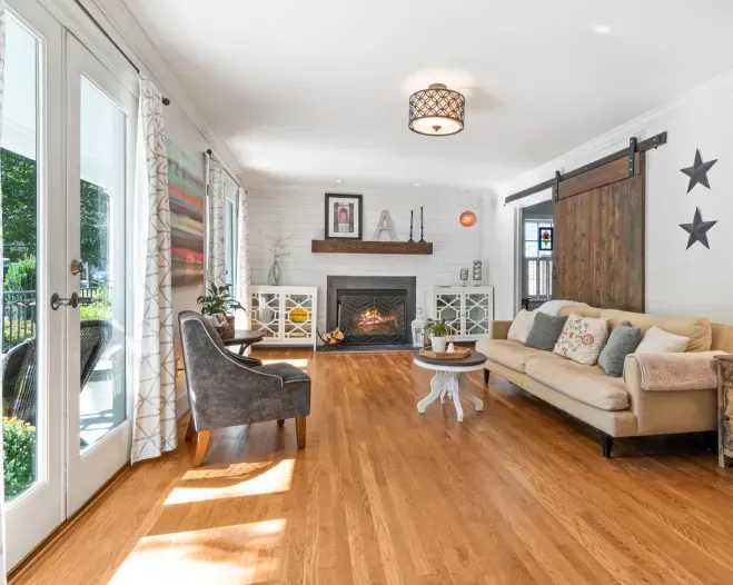 A living room with hardwood floors , a couch , chairs and a fireplace.
