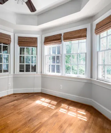 An empty room with a lot of windows and a ceiling fan.