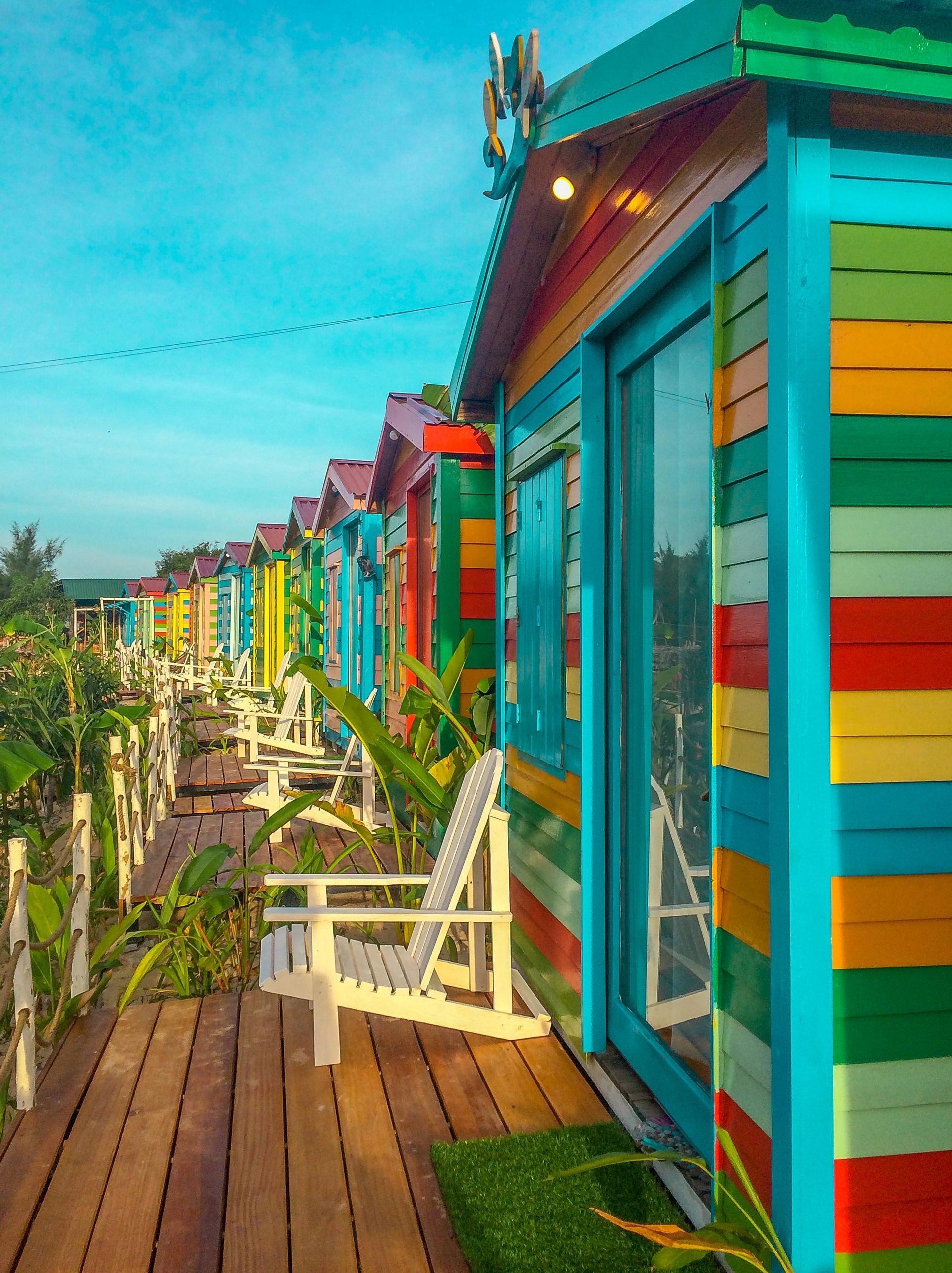 A row of colorful houses with chairs on a wooden deck.