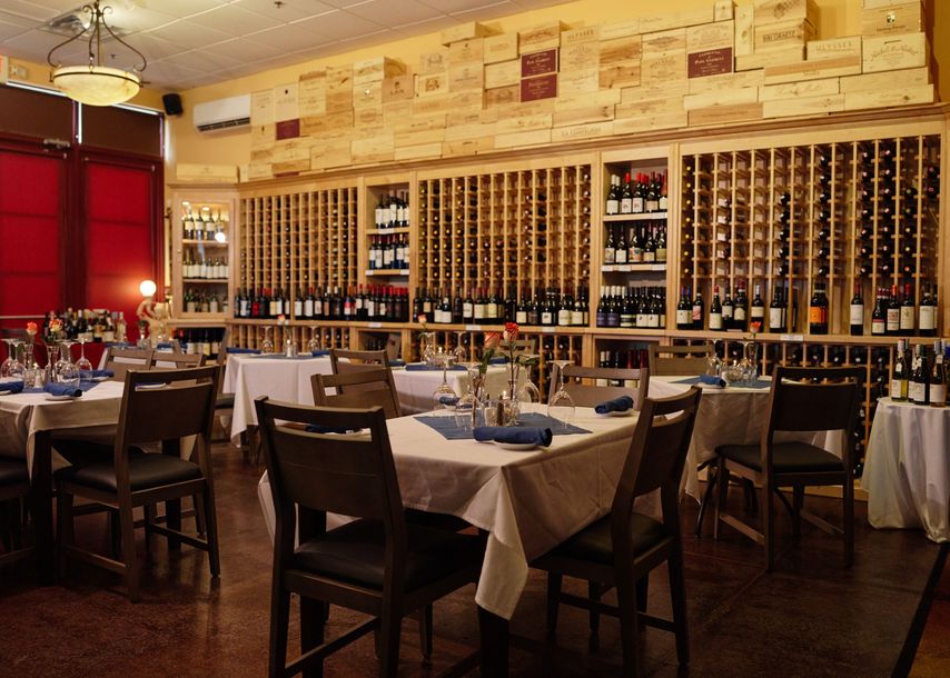 A restaurant with tables and chairs and lots of wine bottles
