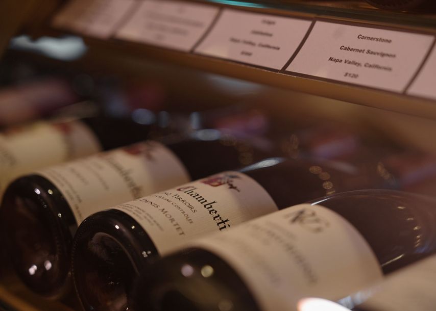 Several bottles of wine are lined up on a shelf and one of them has a label that says gambetti
