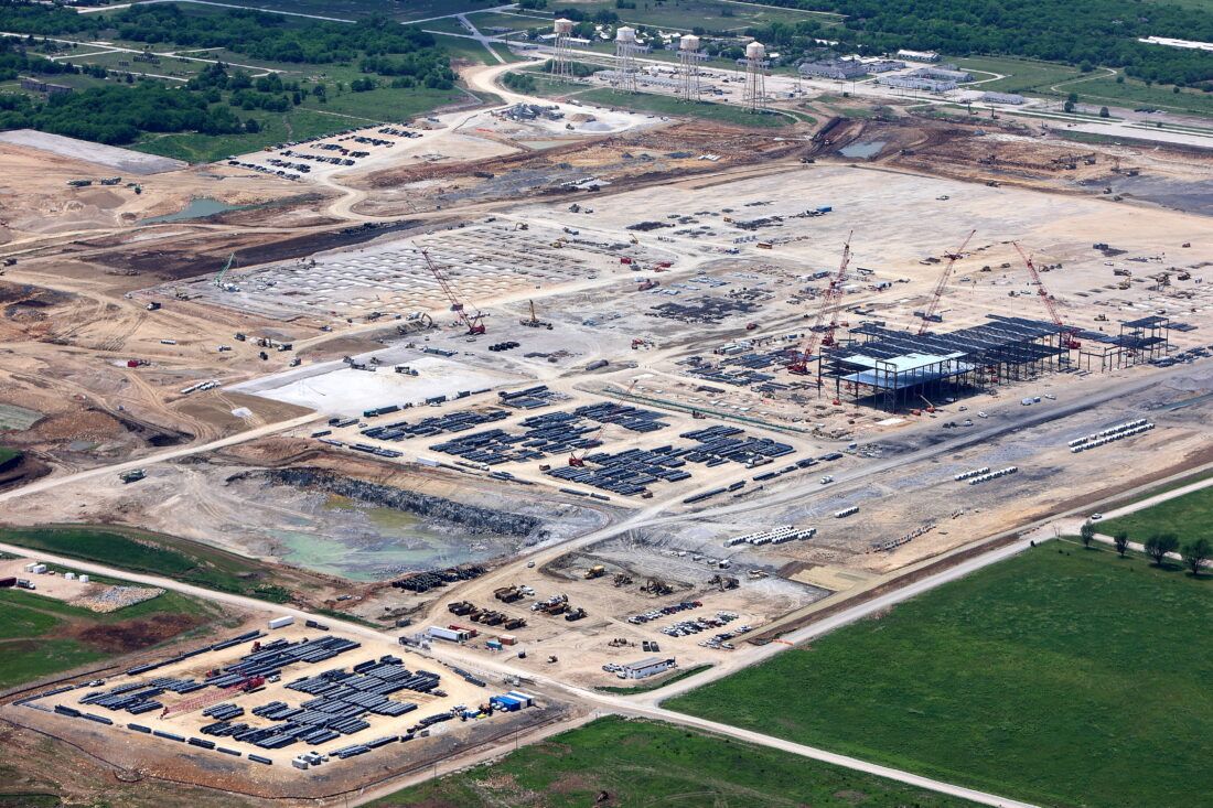 An aerial view of a large construction site with lots of cars parked on the ground.
