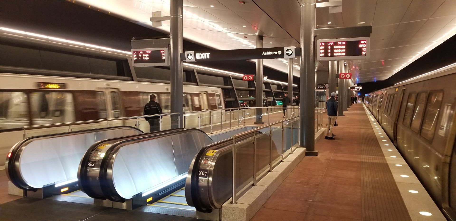A subway station with escalators and a train.