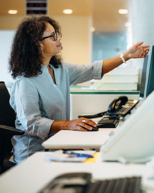 A woman is sitting at a desk in front of a computer.