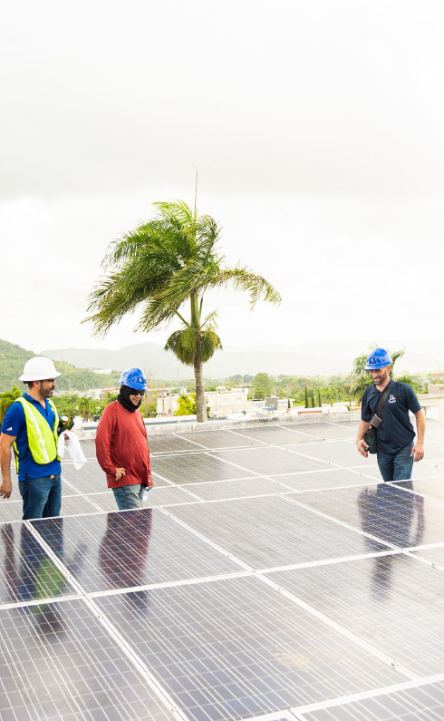 A group of men are standing on in front of many solar panels