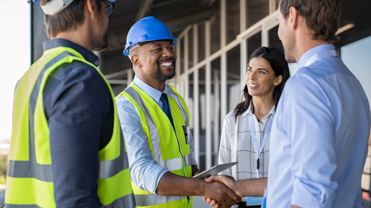 A group of construction workers are shaking hands with a businessman.