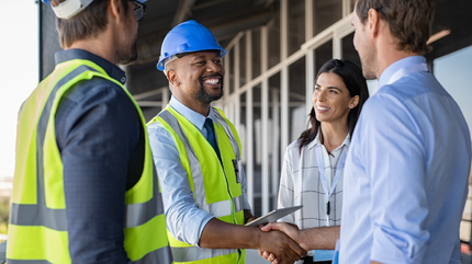 A group of construction workers are shaking hands with a businessman.