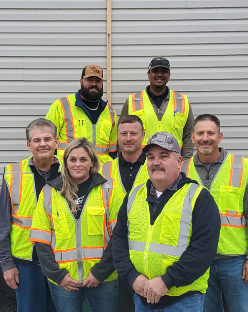 A group of construction workers are posing for a picture in front of a building.