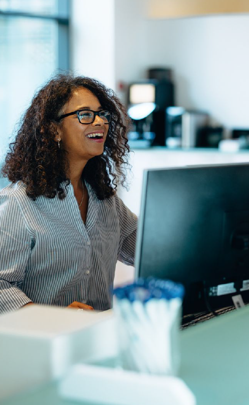 A woman is sitting at a desk in front of a computer.