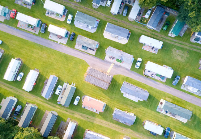 An aerial view of a row of trailers parked in a grassy field.