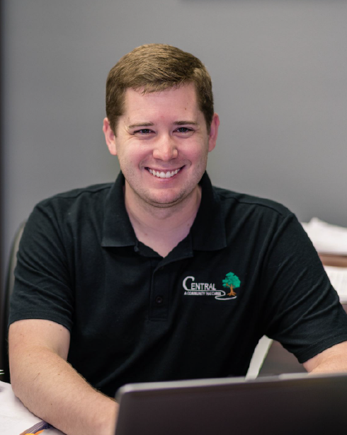 A man wearing a black shirt sitting and smiling