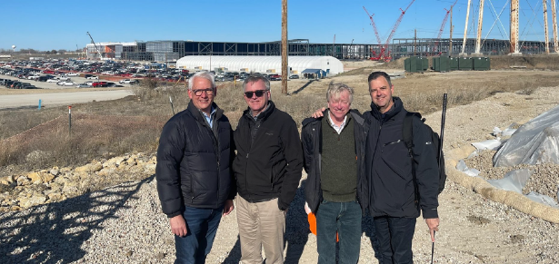 A group of men are posing for a picture in front of a building under construction.