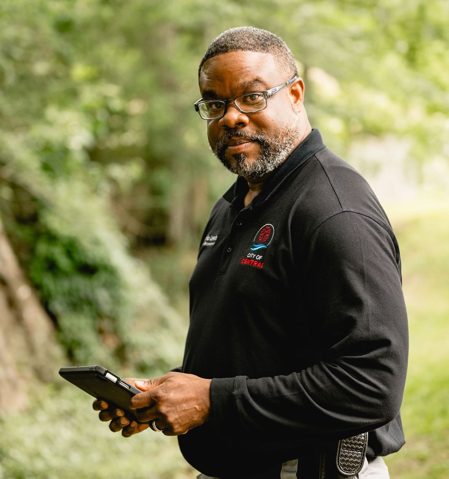 A man in a black shirt is holding a tablet in his hand.
