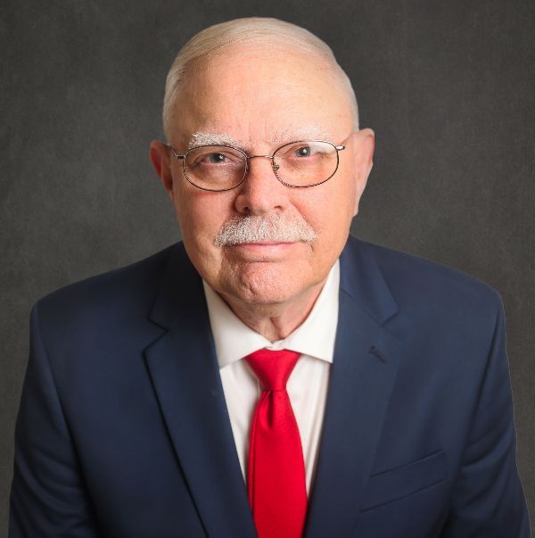 A man in a suit and tie with glasses and a mustache.