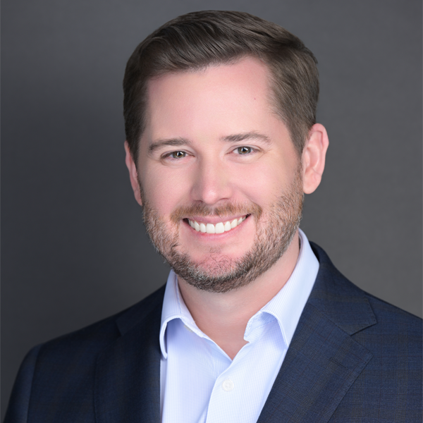 A man in a suit and blue shirt is smiling for the camera.