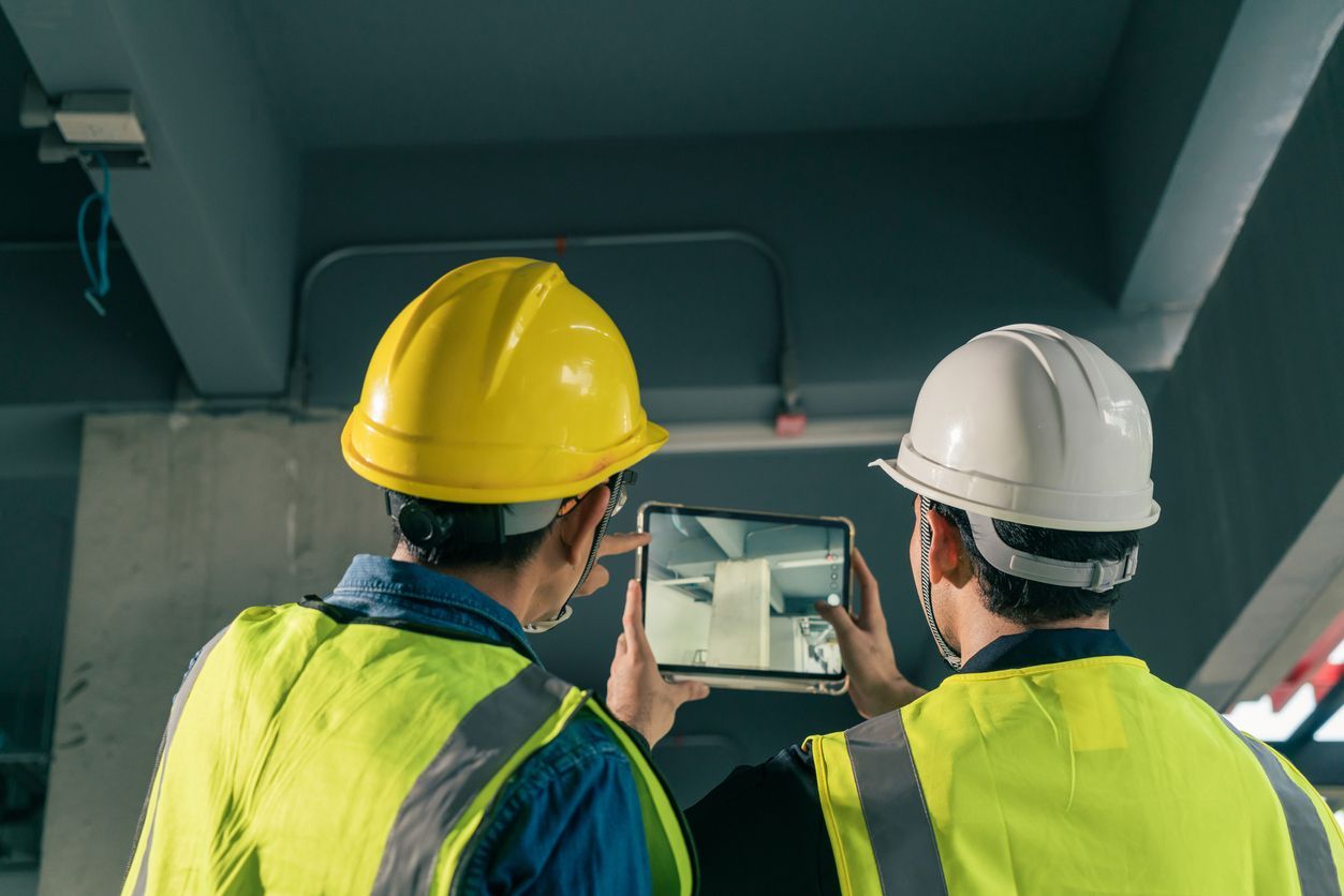 Two construction workers are looking at a tablet.