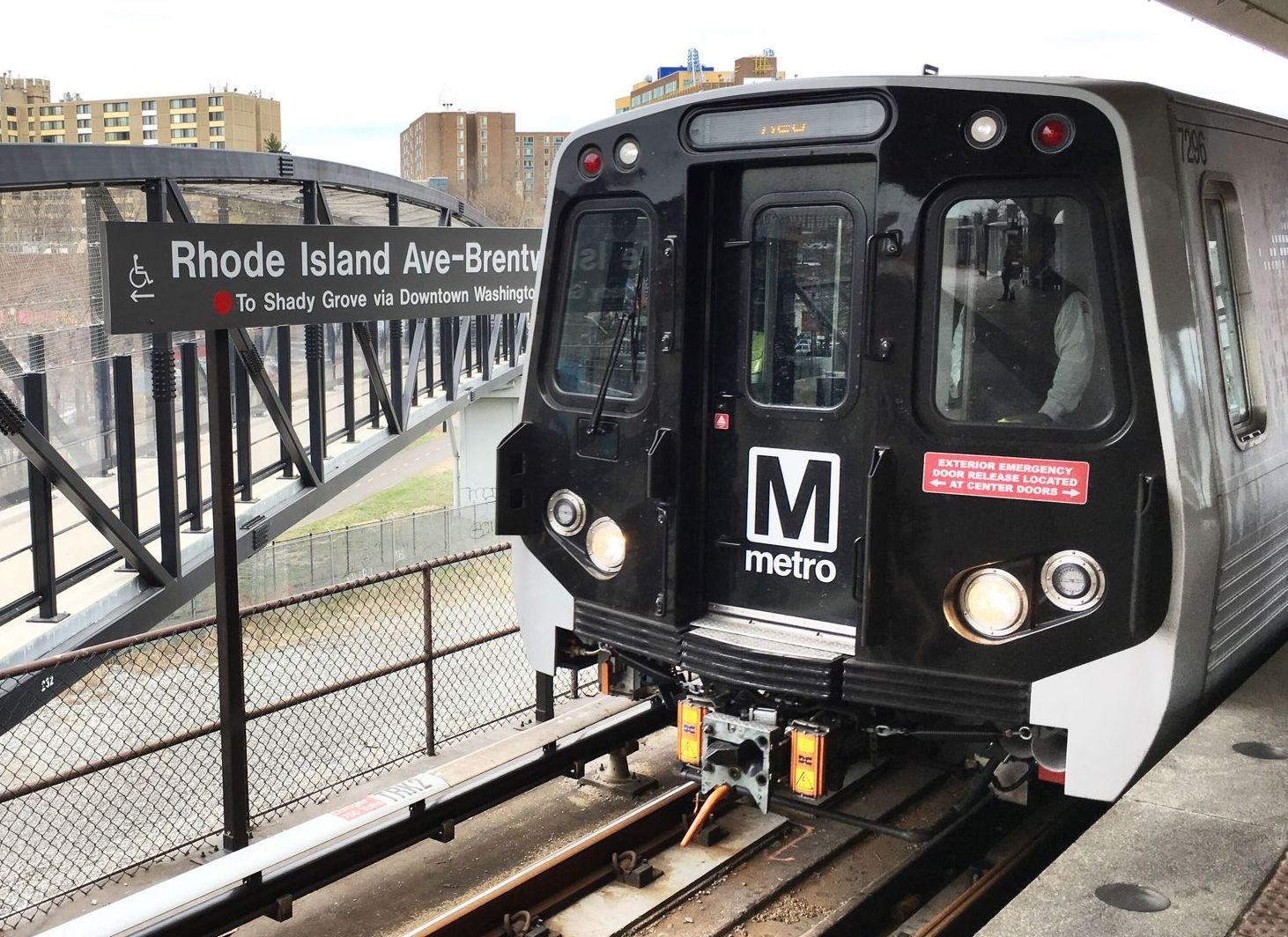 A metro train is sitting on the tracks at a station.