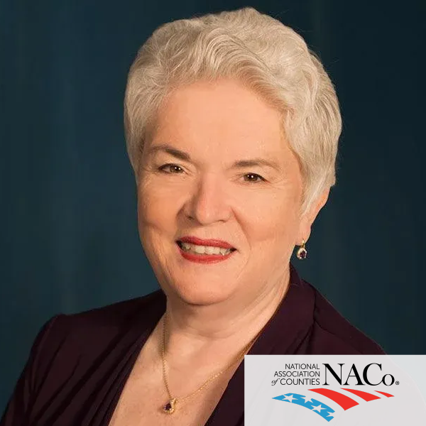 A woman is smiling in front of a naco logo