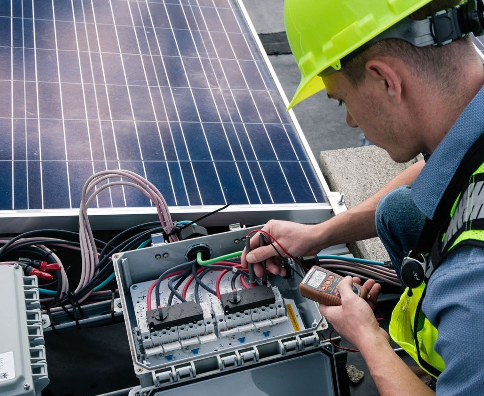 A man wearing a hard hat is working on a solar panel
