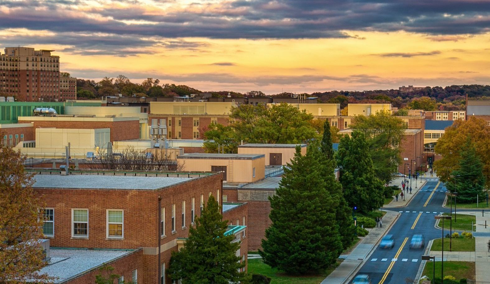 An aerial view of a city street with a sunset in the background.