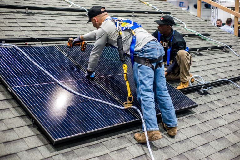 Two men are installing solar panels on a roof.