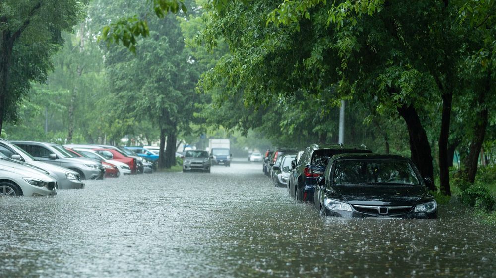 A flooded parking lot with cars parked in the water.