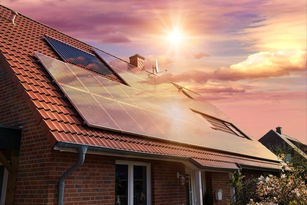 A brick house with solar panels on the roof at sunset.