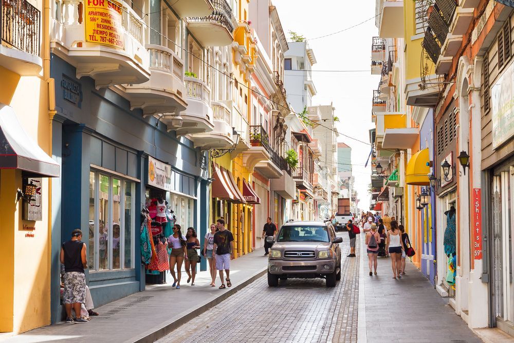 A car is driving down a narrow street in puerto rico.