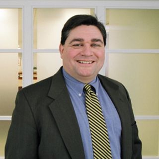 A man in a suit and tie is smiling for the camera