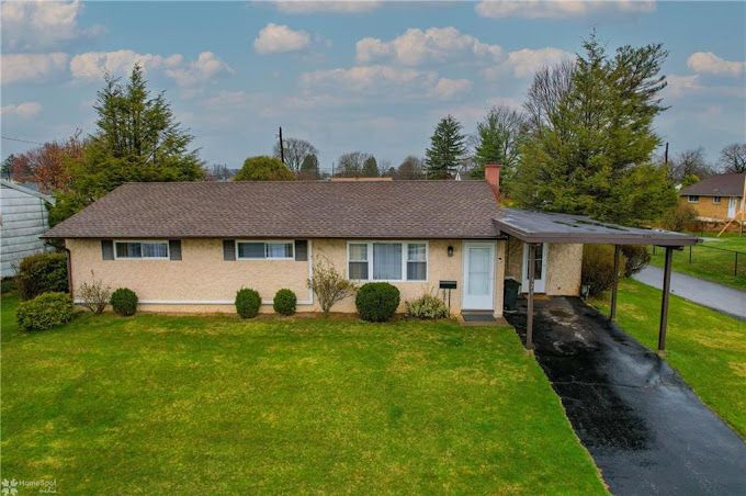 An aerial view of a house with a large lawn and a driveway.