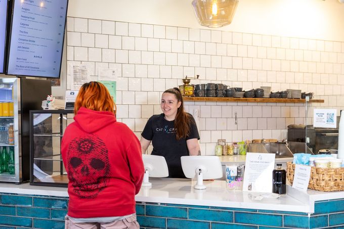 A woman in a red hoodie is standing at a counter in a restaurant.