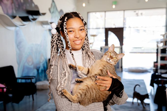 A woman with dreadlocks is holding a cat in her arms.