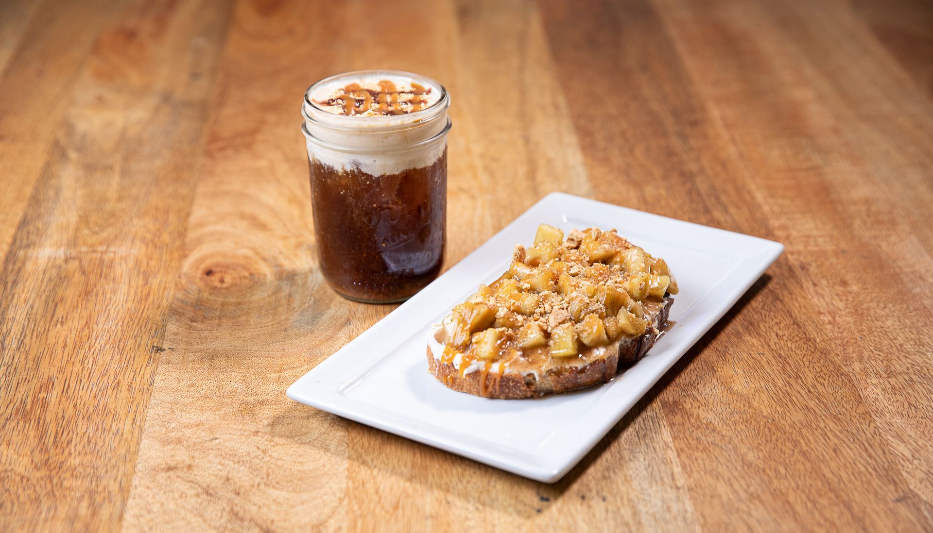 A plate of food and a glass of coffee on a wooden table.
