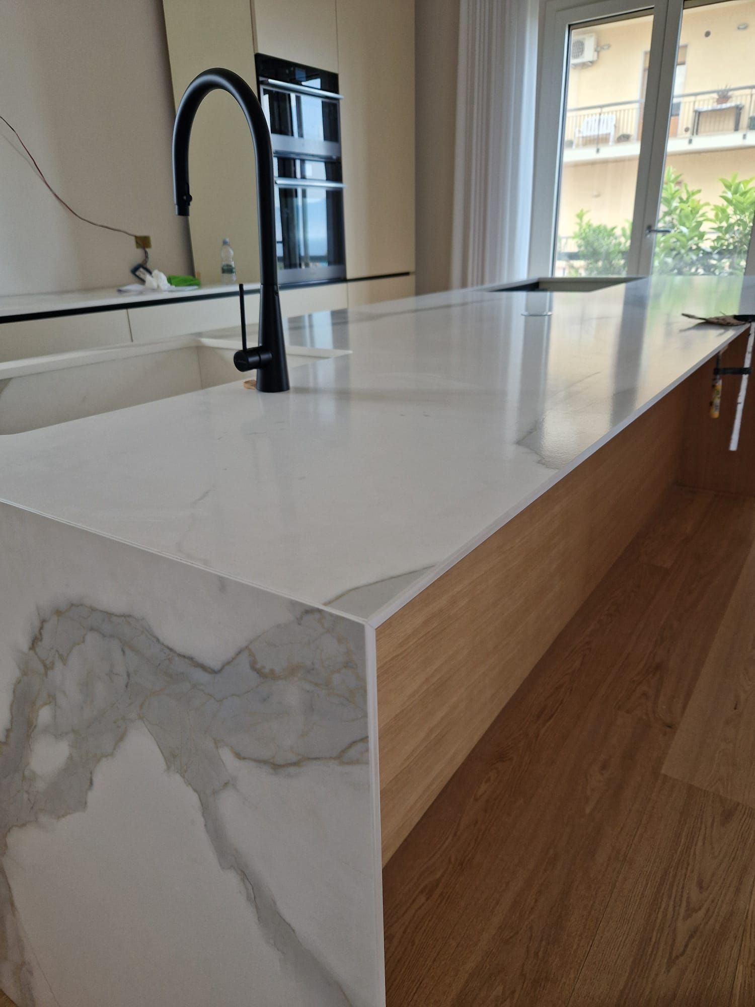 Una cucina con un piano di lavoro in marmo e un rubinetto nero.