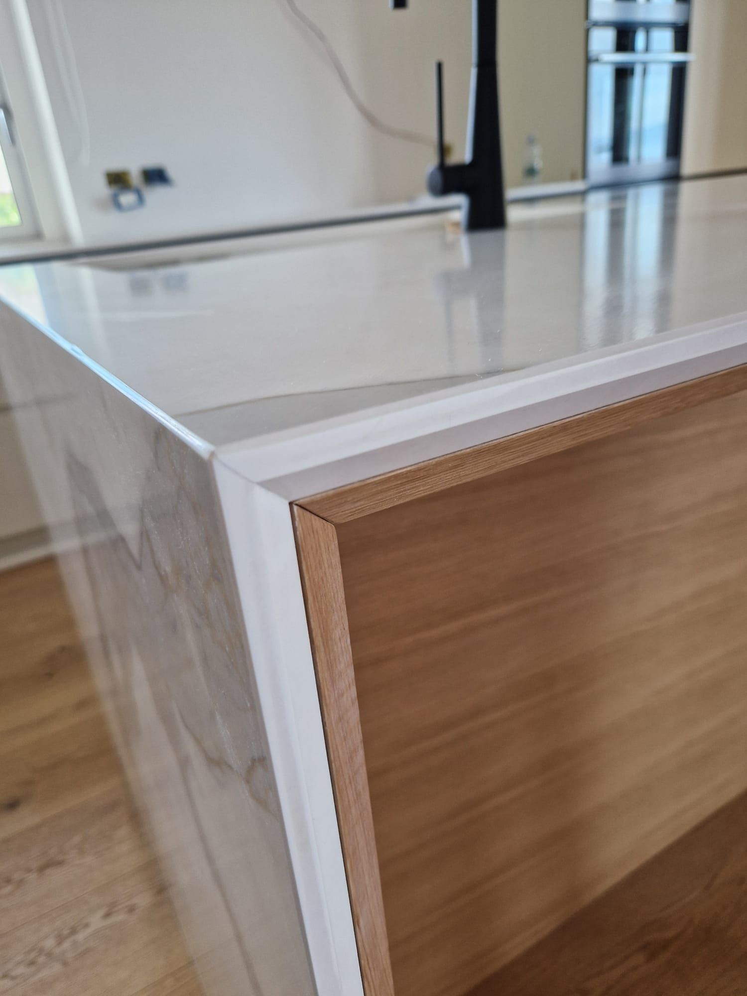 Un'isola della cucina con un piano di lavoro bianco e mobili in legno.