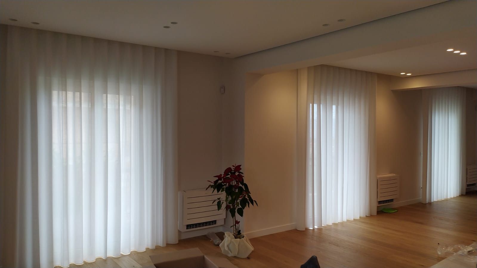 Un soggiorno con tende bianche e un vaso di fiori.