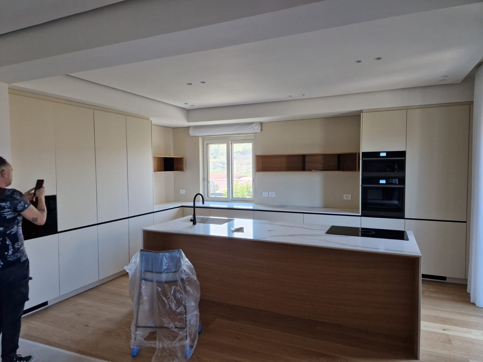 Un uomo sta scattando una foto di una cucina con un telefono.