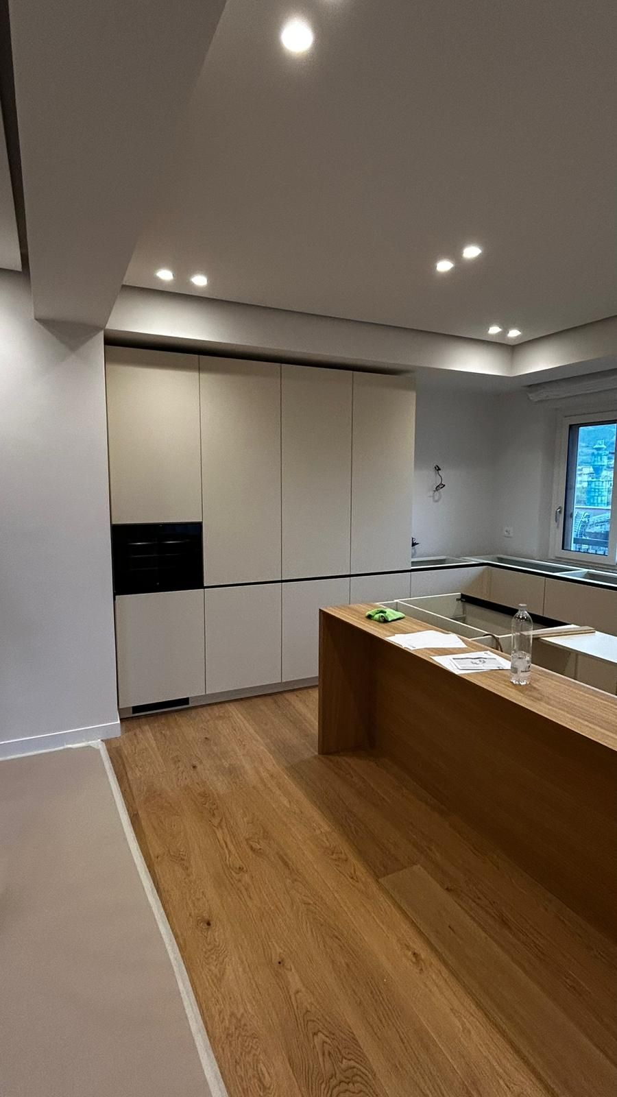 Una cucina con mobili bianchi e un piano di lavoro in legno.