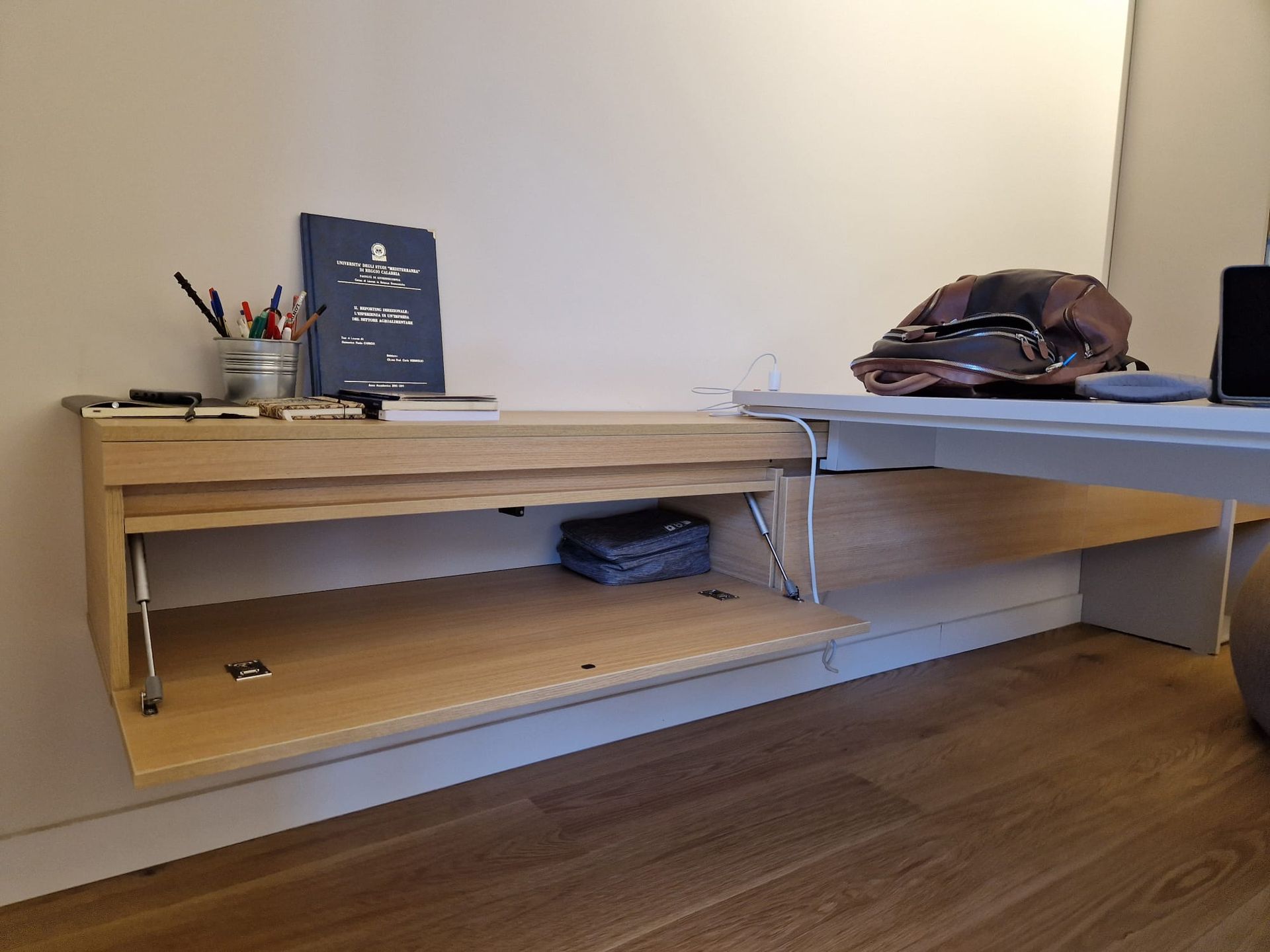 Una scrivania di legno con un computer portatile sopra in una stanza.