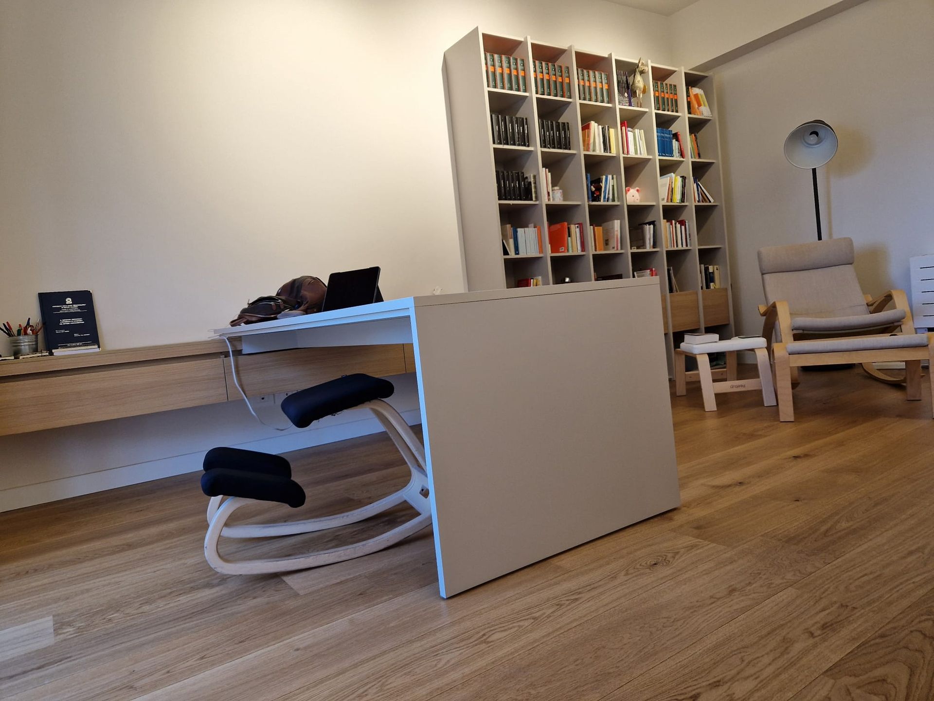 Un soggiorno con scrivania, sedie e libreria.