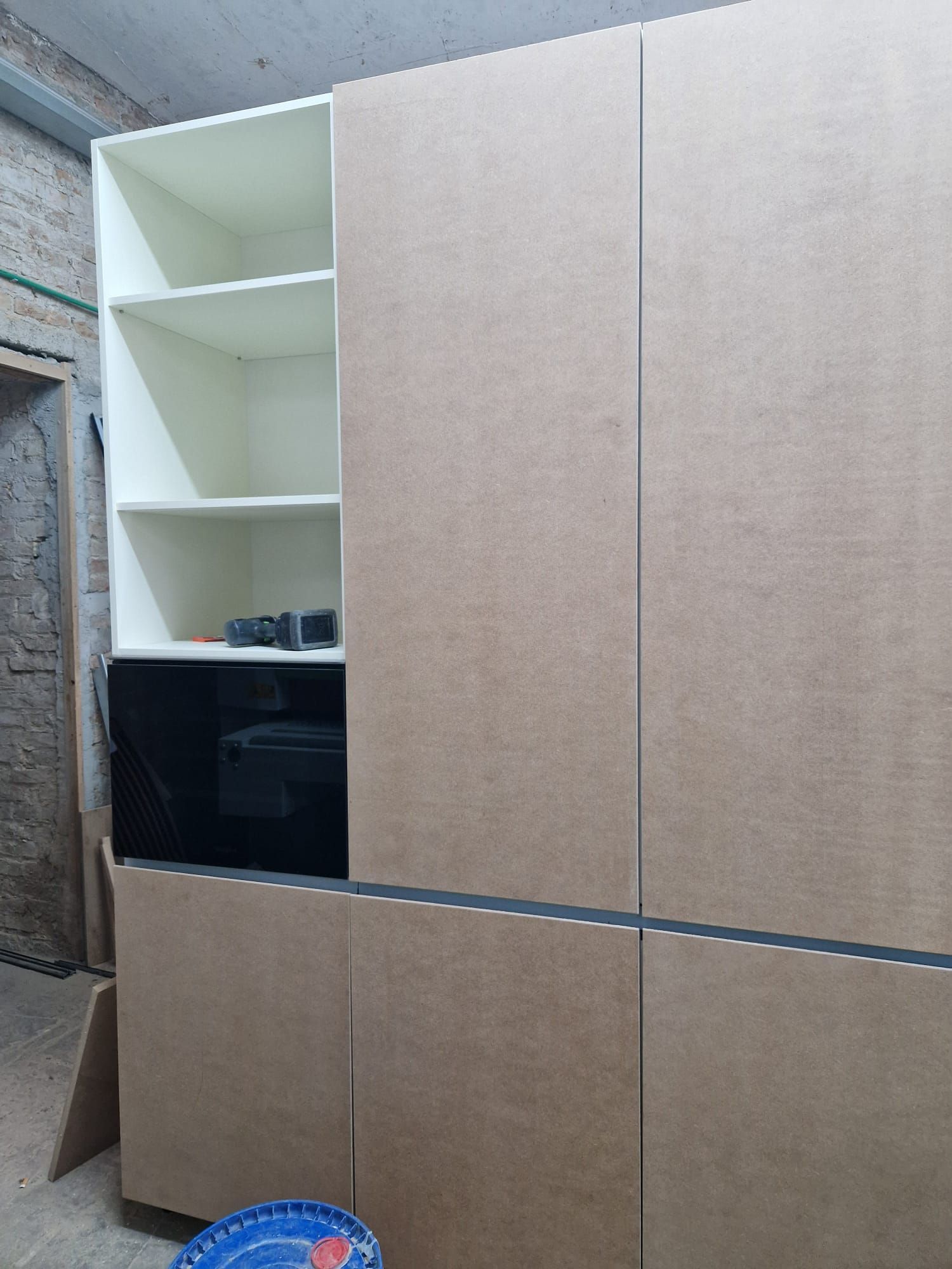 Un mobiletto di legno con ripiani e un forno a microonde in una stanza.