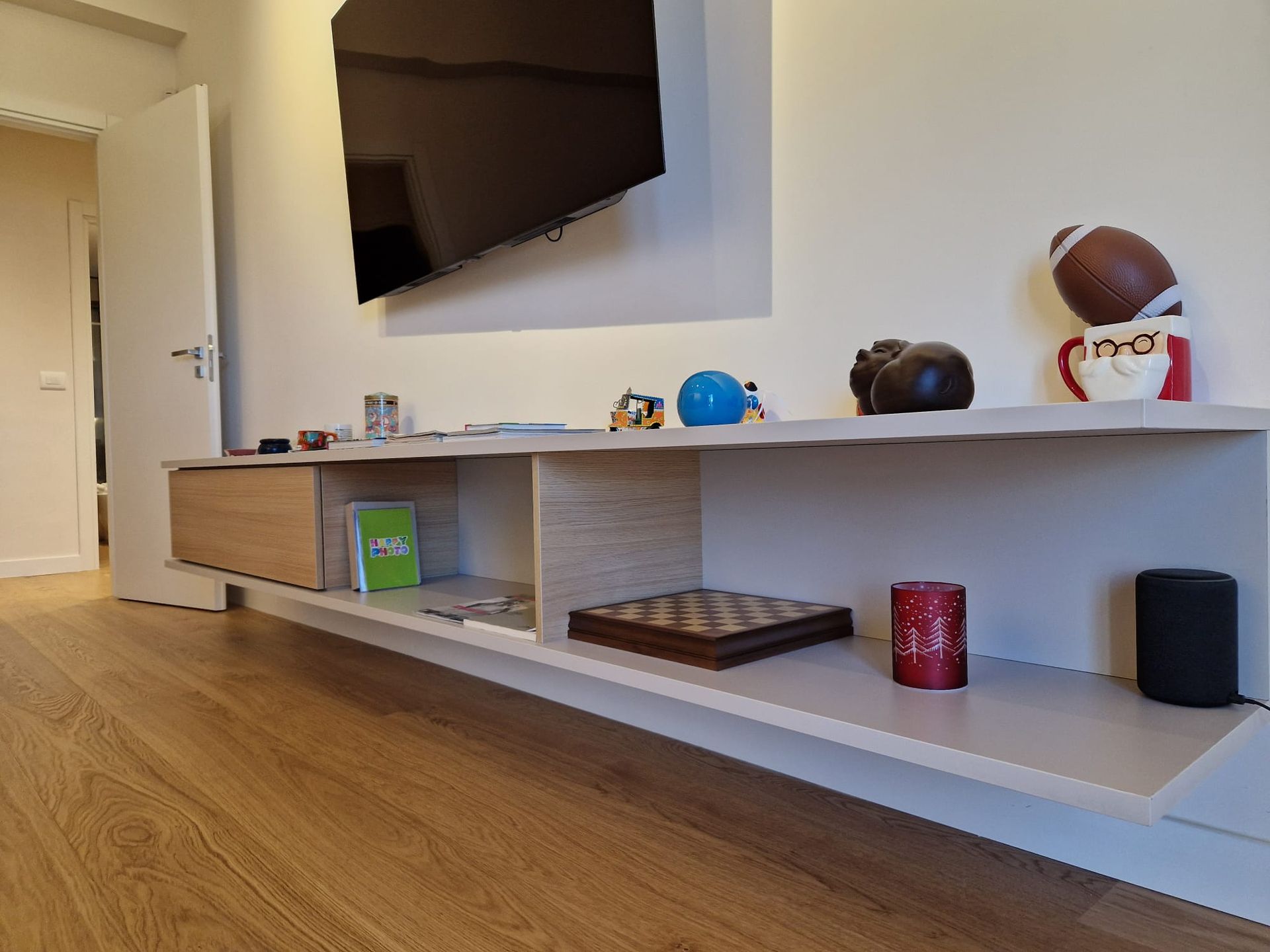 Un soggiorno con una TV a schermo piatto e uno scaffale con i giocattoli.