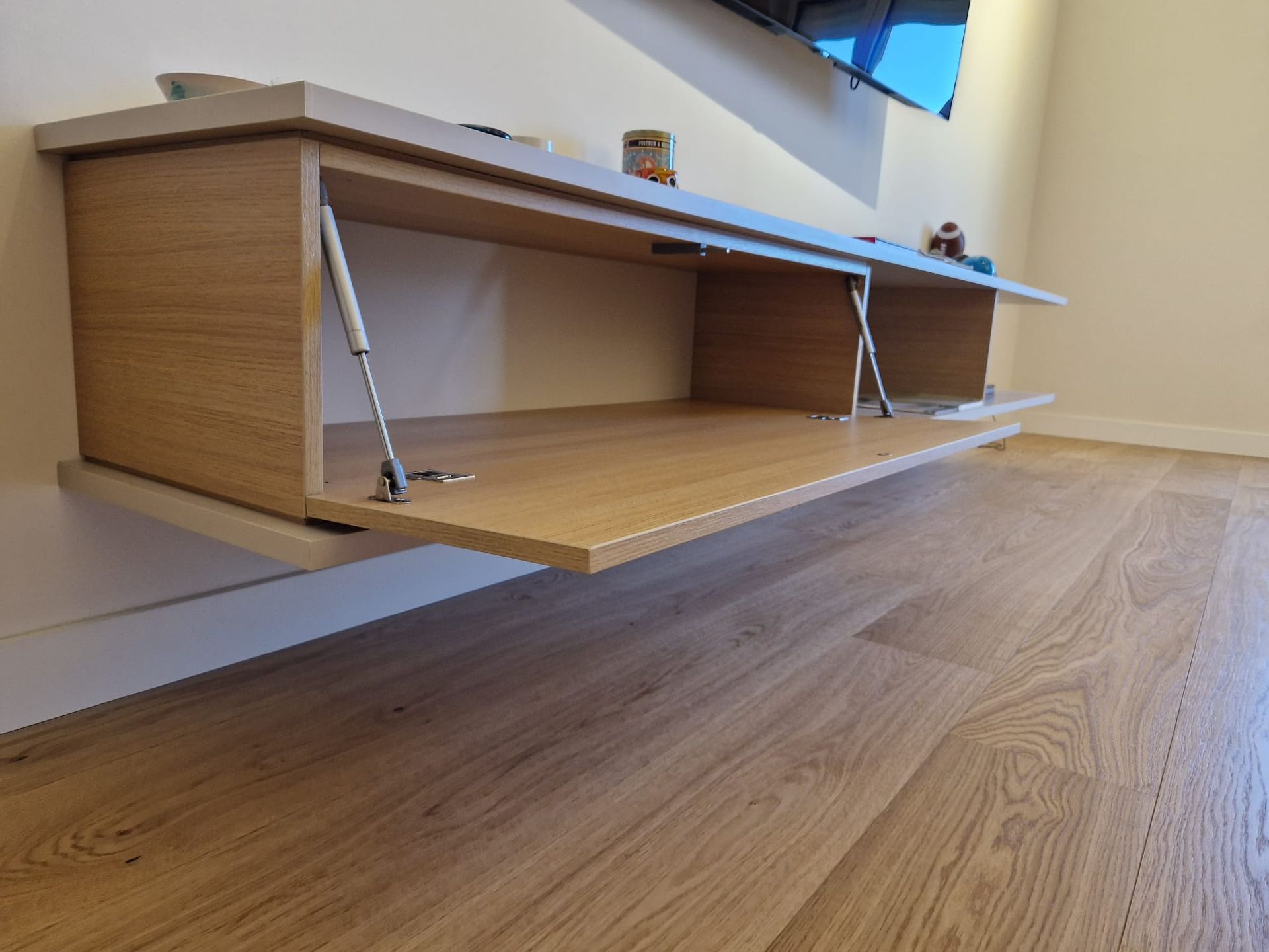 Un mobile porta TV in legno è appeso al muro con la porta aperta.