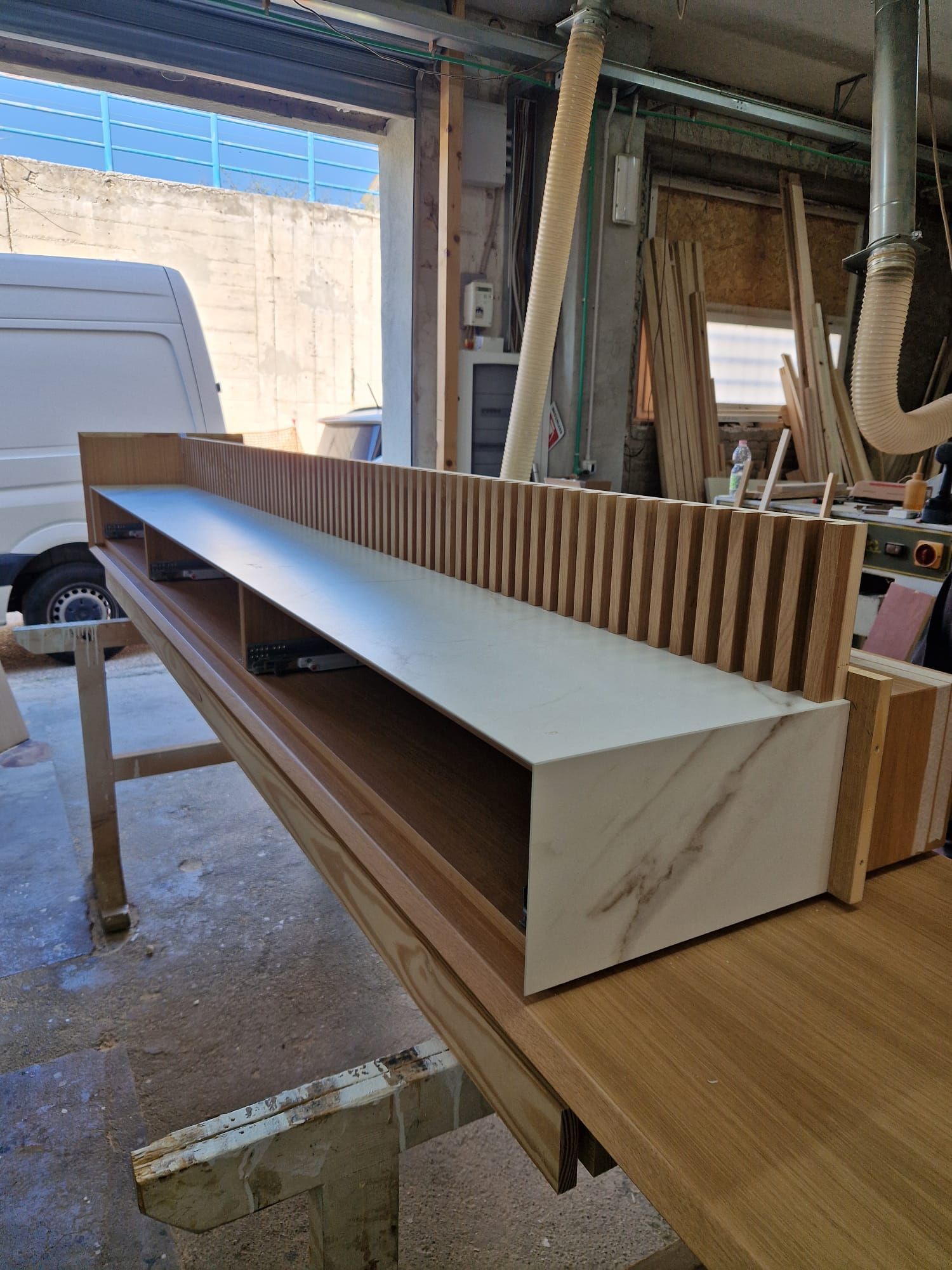 Un tavolo di legno è appoggiato in un garage accanto a un furgone bianco.