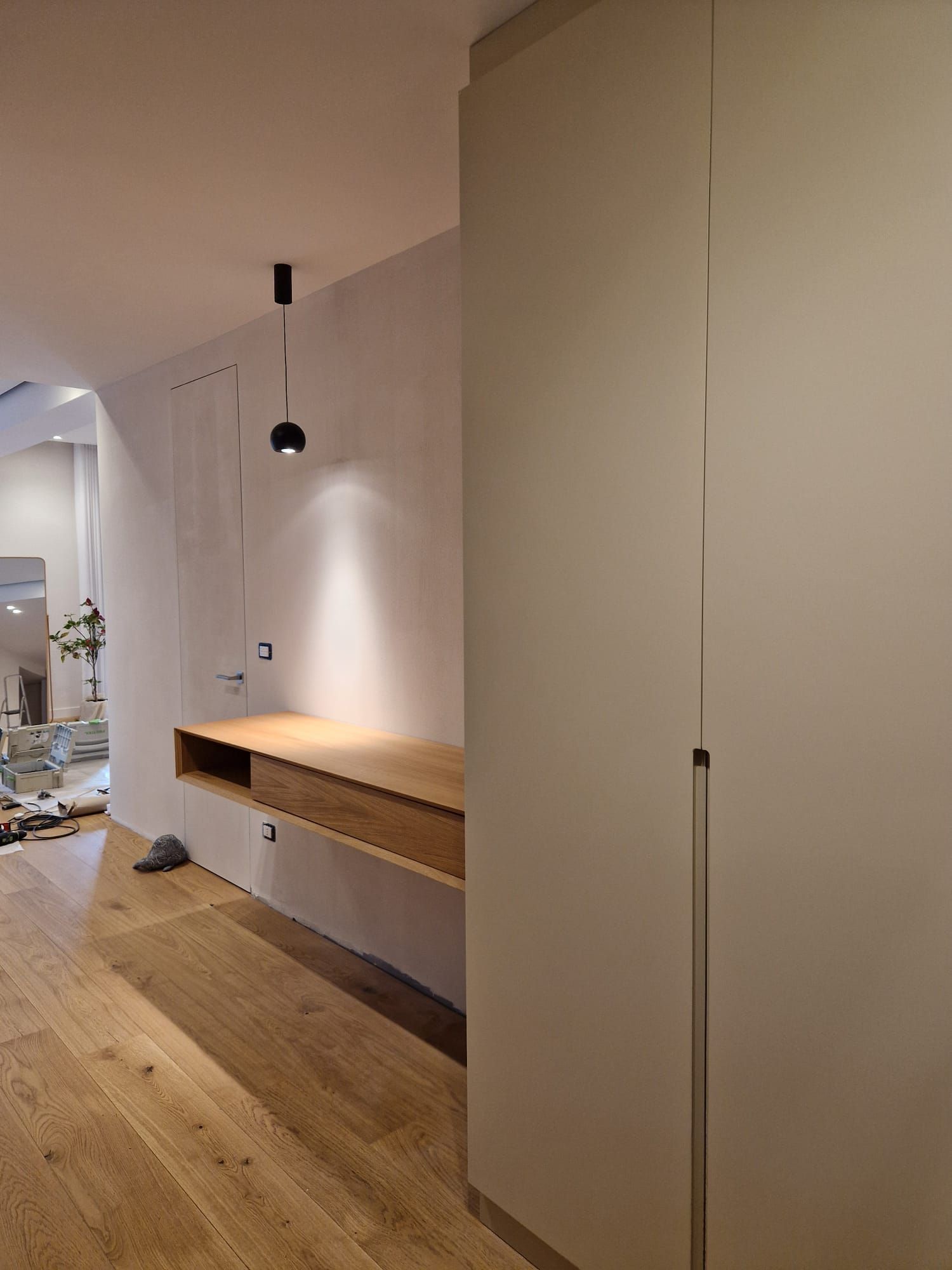Un corridoio con pavimento in legno e armadi bianchi