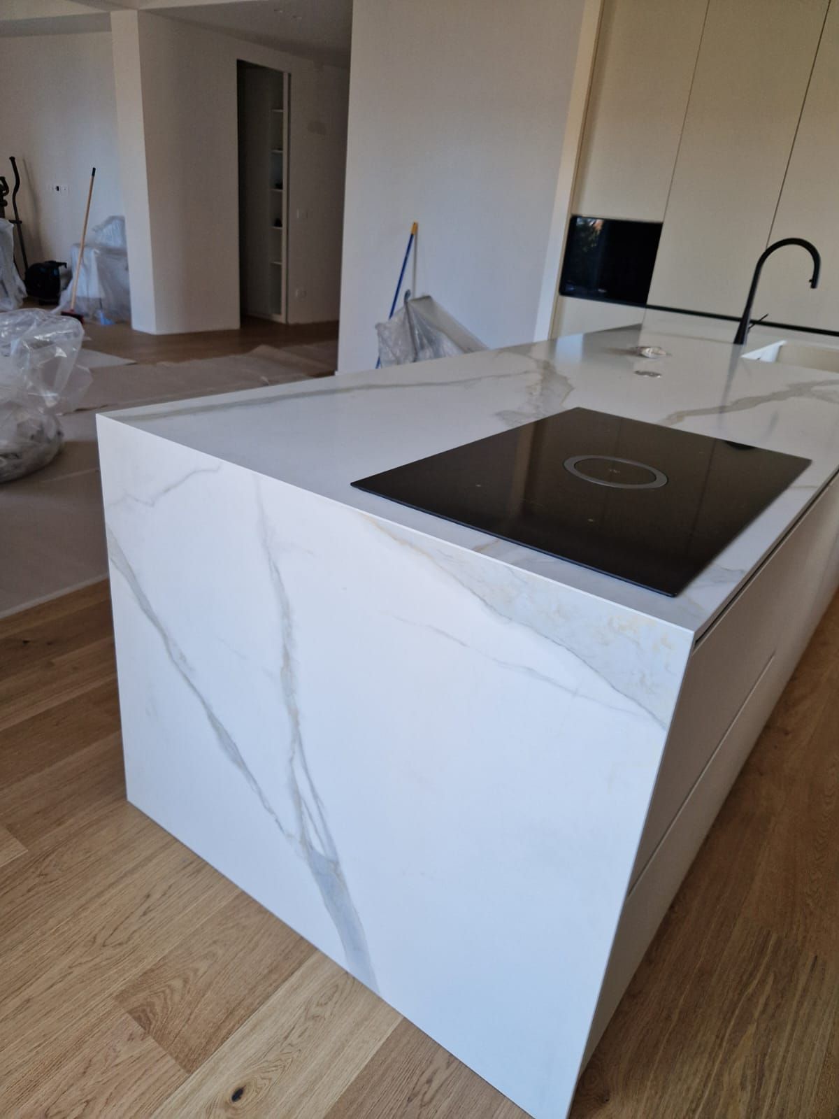 Una cucina con un piano di lavoro bianco e un forno nero.