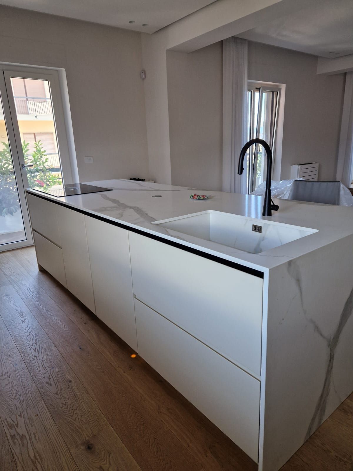 Una cucina con mobili bianchi, un lavandino e una finestra.