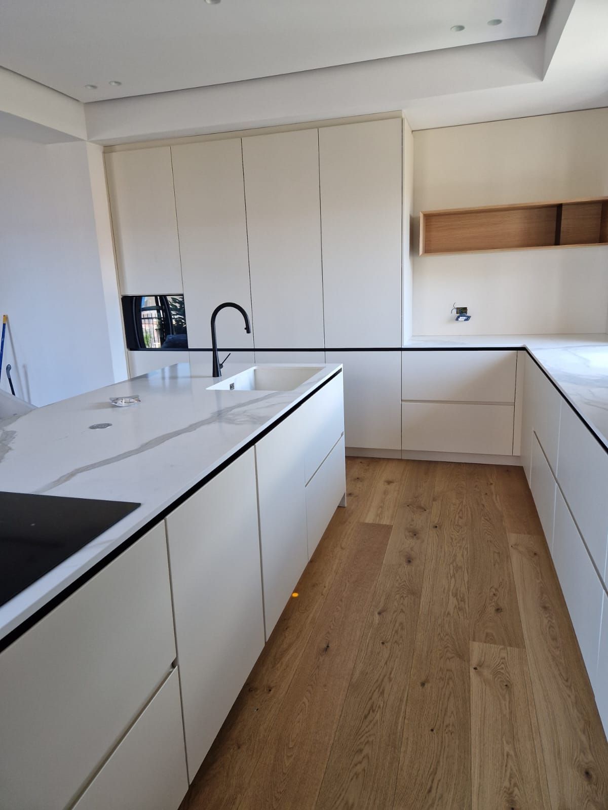 Una cucina con mobili bianchi e pavimenti in legno