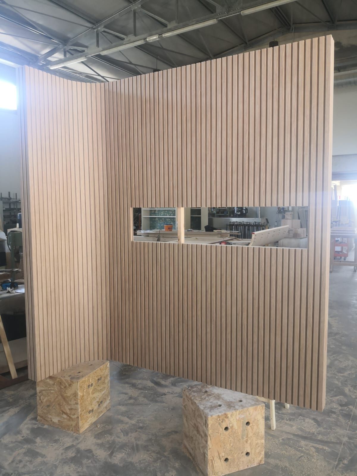 In una fabbrica viene costruito un muro di legno con una finestra.