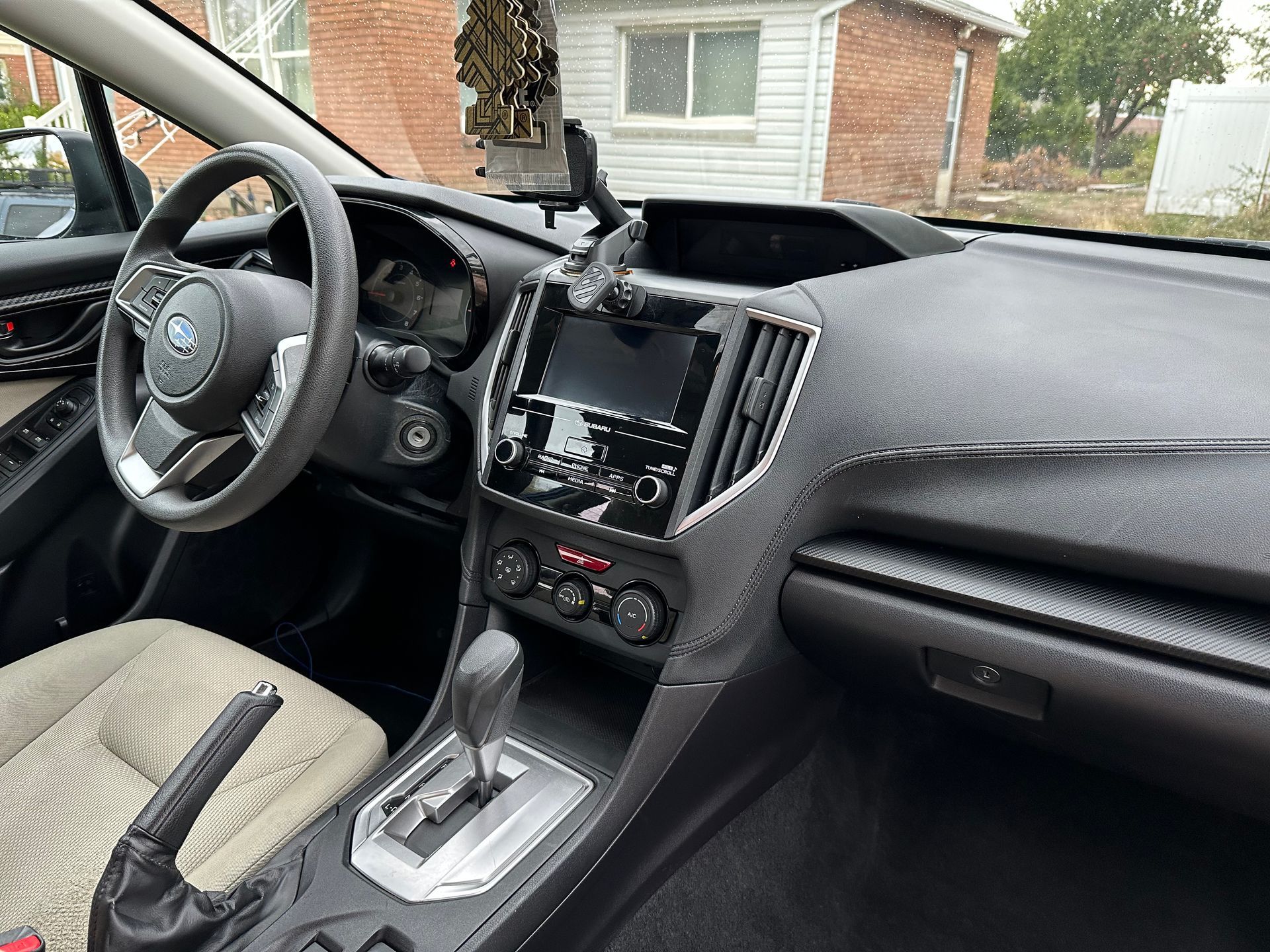 Interior view of a Subaru car; beige seats, black dashboard, steering wheel, infotainment screen.